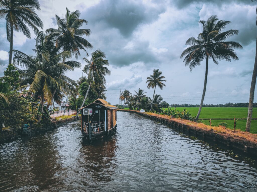 Scenic houseboat on a tranquil canal surrounded by lush palm trees in Kerala, India.