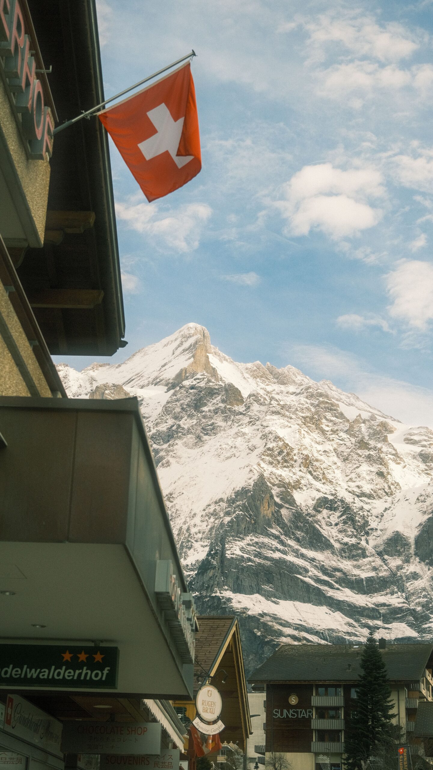 Majestic Swiss Alps in Grindelwald with a distinctive flag, under a blue sky.